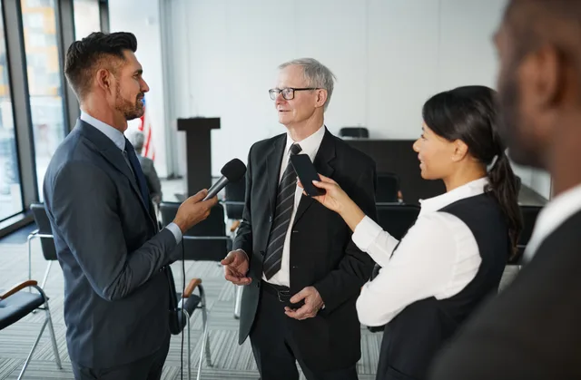 Journalists conduct an interview with a senior executive in a formal office setting. Press release distribution vendor due diligence checklist